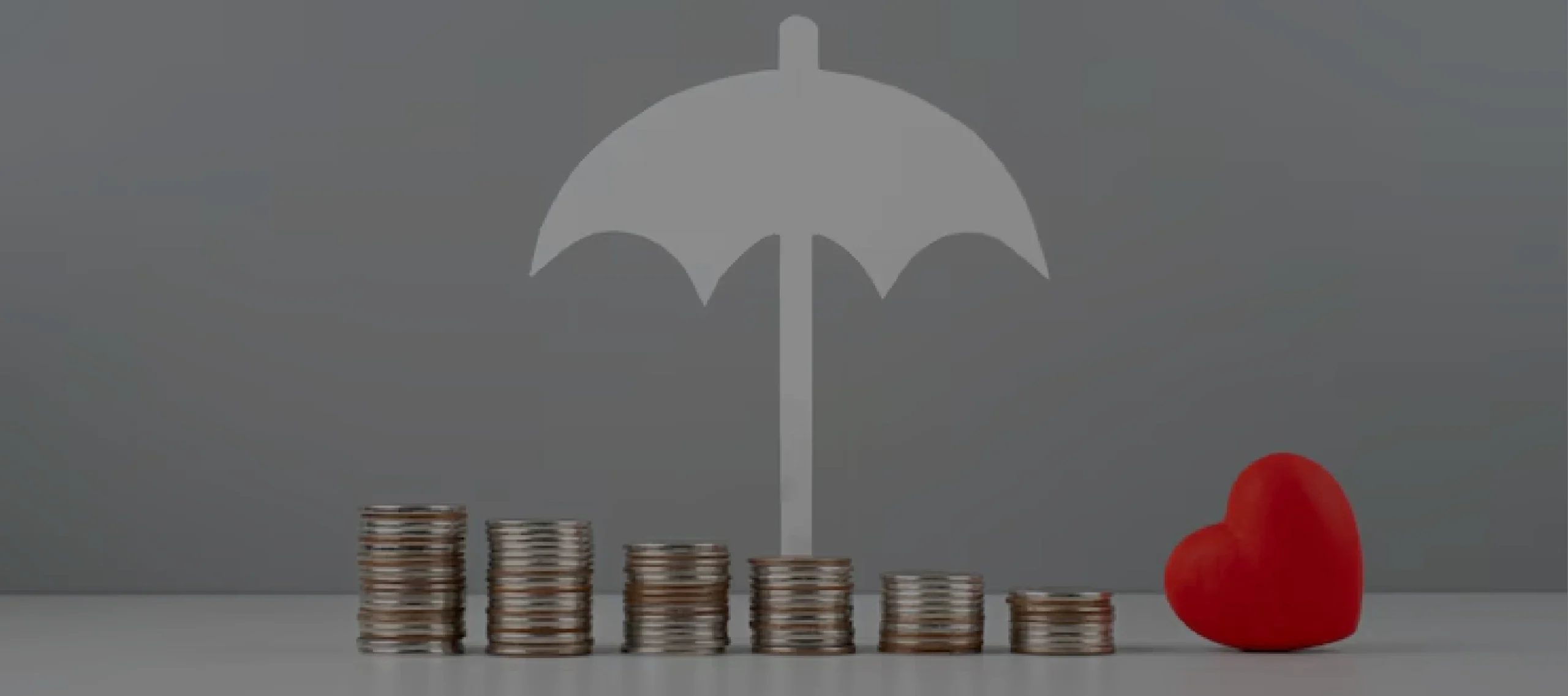 Stacks of coins protected under an umbrella icon with a heart symbolizing affordable umbrella insurance coverage for finances and well-being
